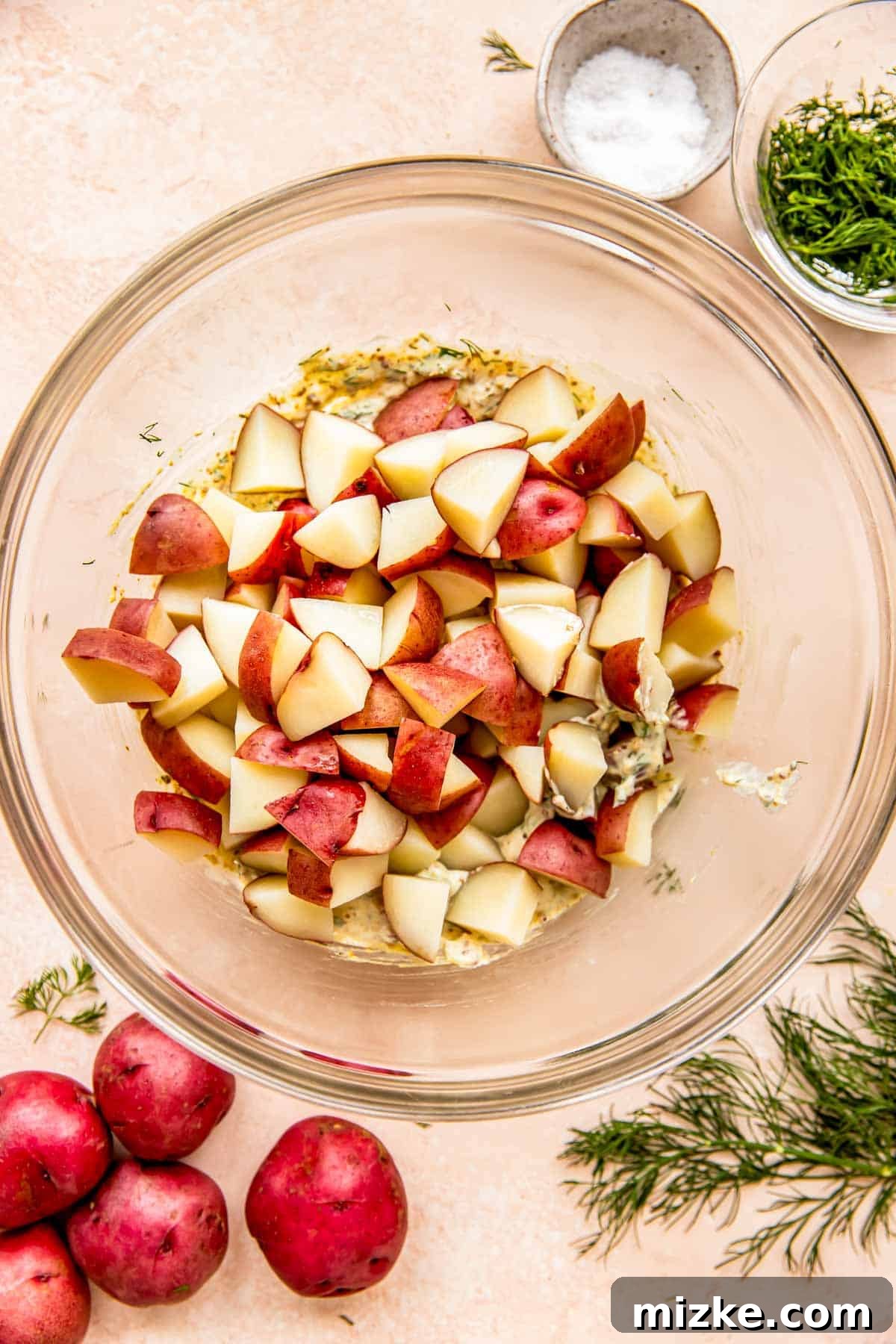 Zesty Dill Potato Salad 6 Perfectly cooked and cooled chopped red potatoes are added to a large glass mixing bowl, ready for the dressing.