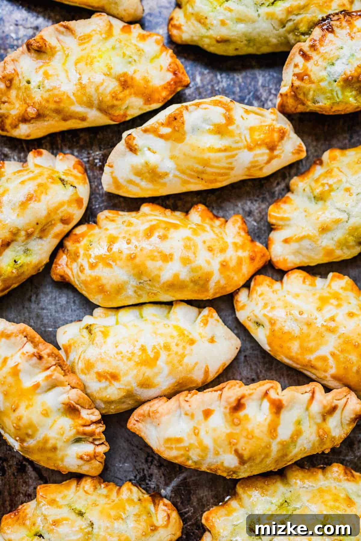 Chinese Curry Pockets are a traditional snack that tucks curried beef and potatoes into circles of dough, then bakes them to flaky perfection! Overhead shot of perfectly baked Chinese curry pockets, golden and flaky, on a sheet pan.