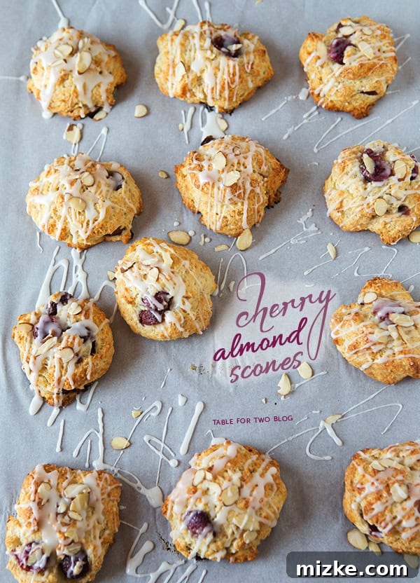 Cherry Almond Scones | tablefortwoblog.com Freshly baked cherry almond scones on a cooling rack, drizzled with glaze.