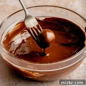 Dipping a peanut butter ball into chocolate with a fork.