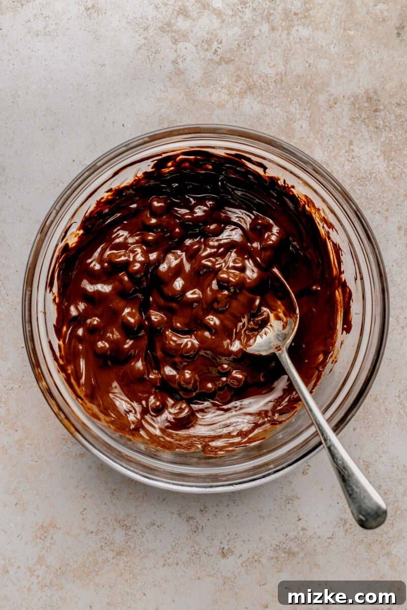 Creamy peanut butter sweetened with powdered sugar is rolled into balls and coated in chocolate to make these decadent peanut butter balls. Dark chocolate chips and coconut oil melting together in a microwave-safe bowl, becoming a smooth, glossy coating.
