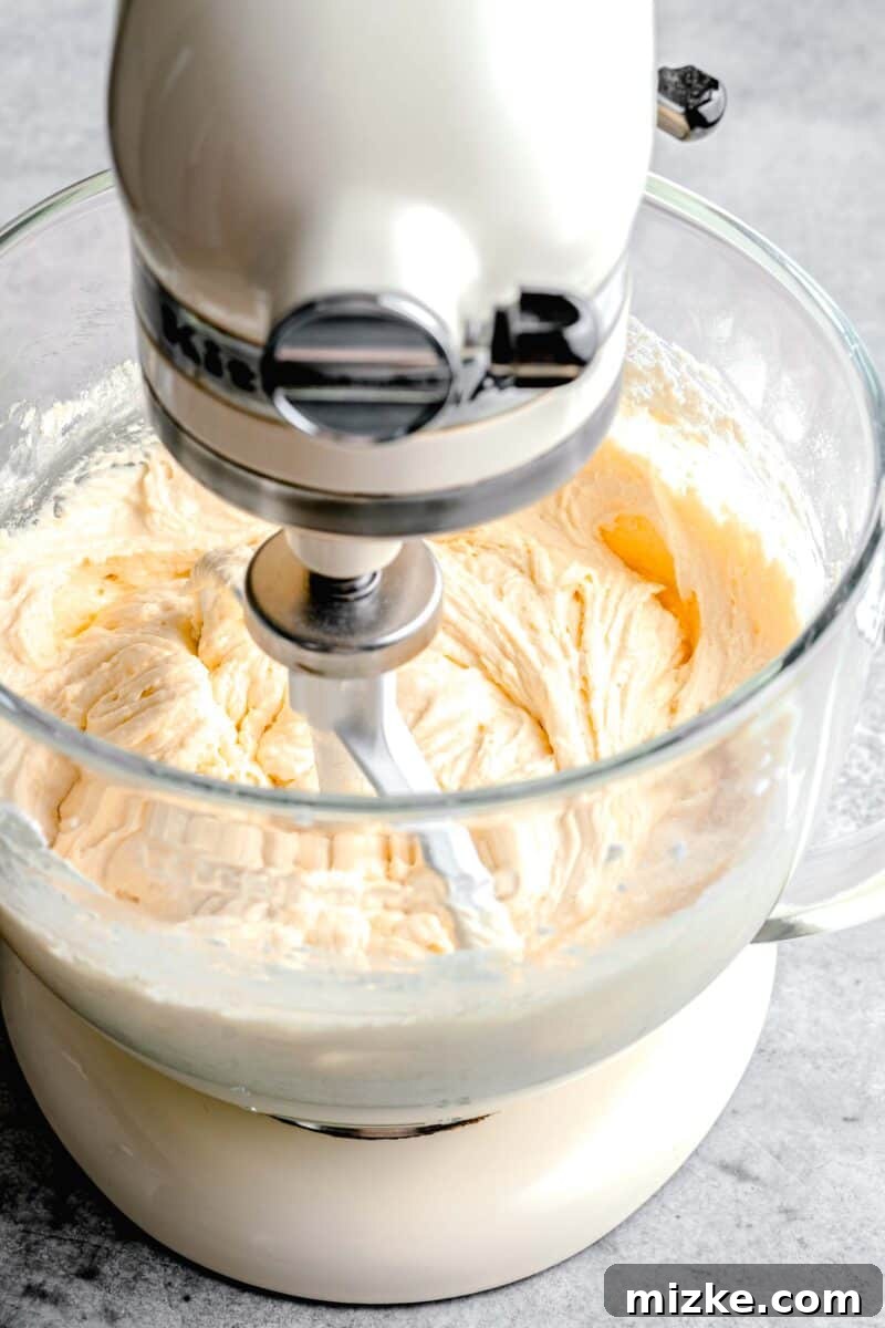 Blueberry Burst Bundt 5 Smooth cake batter being expertly mixed in a stand mixer, showcasing its creamy and well-aerated texture, ready for the next steps.