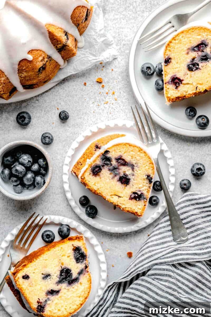 Blueberry Burst Bundt 8 Individual slices of moist blueberry bundt cake elegantly plated on several white dishes, ready to be enjoyed, highlighting the perfect crumb and glaze.