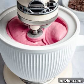 Stand mixer blending ice cream in a white bowl, on a kitchen counter.