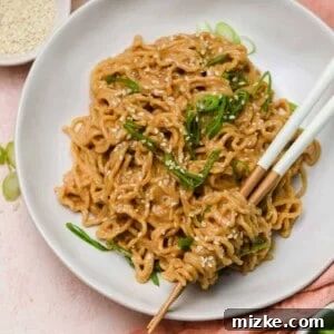 Delicious Cold Spicy Peanut Sesame Noodles in a bowl with fresh garnishes.