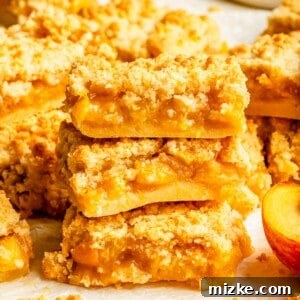 A stack of three peach crumble bars, highlighting their layered goodness, photographed on a clean white background.