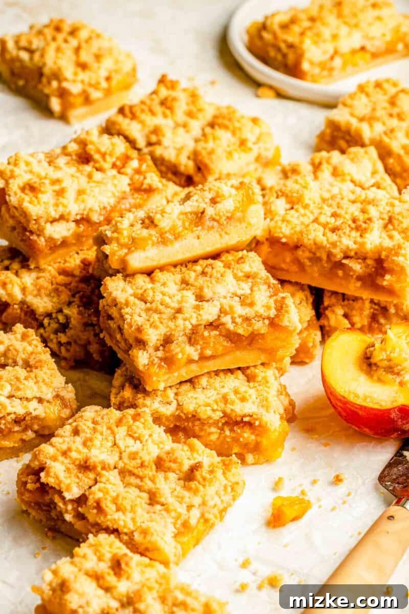 Golden Peach Crumble Squares 9 A fresh batch of golden-brown peach crumble bars, perfectly sliced and arranged, invitingly displayed on a pristine white surface.
