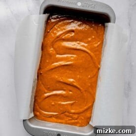 Sweet potato bread batter in a loaf pan lined with parchment paper.