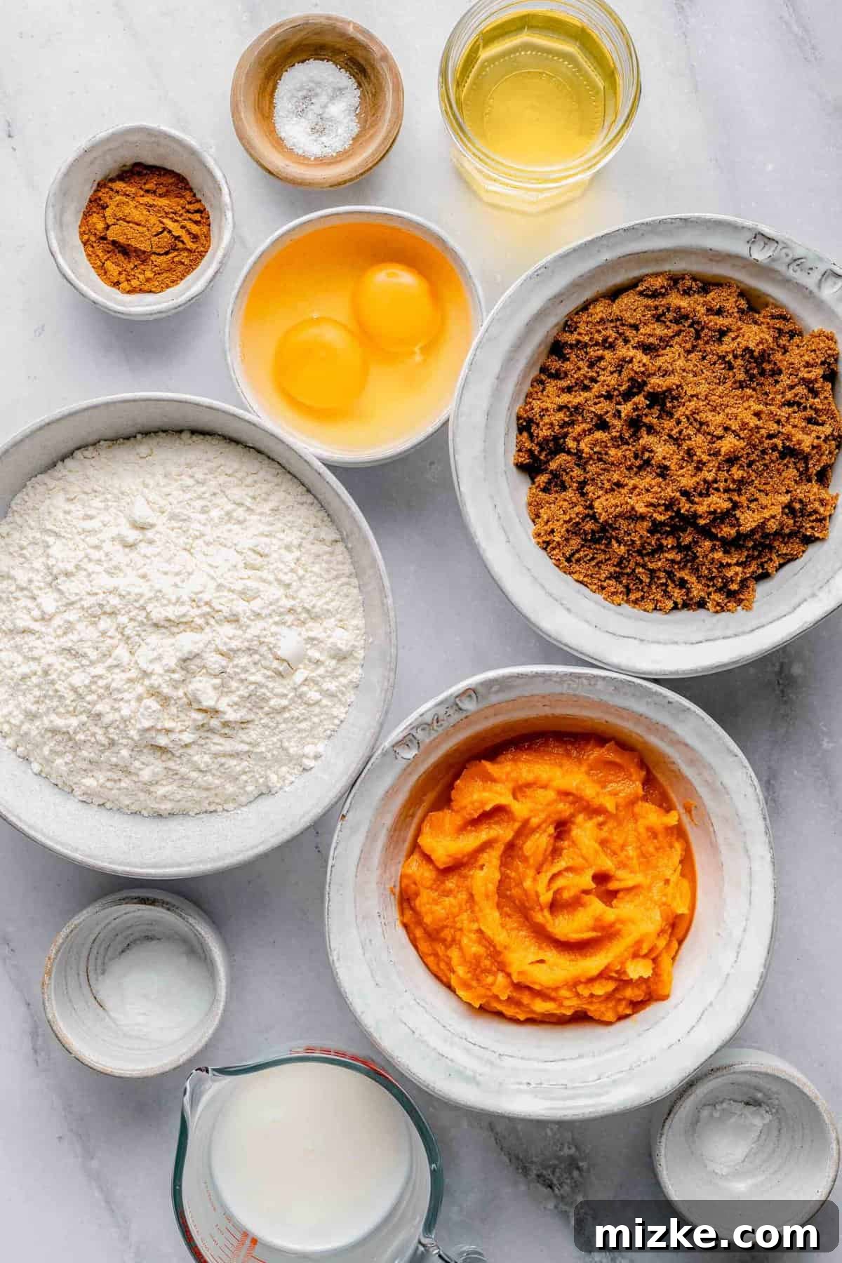 The essential ingredients for crafting the perfect sweet potato bread: mashed sweet potatoes, brown sugar, buttermilk, and pumpkin spice, ensuring a tender, moist, and subtly sweet result. A collection of fresh ingredients laid out on a white surface, including sweet potatoes, flour, sugar, eggs, and spices, all ready for making sweet potato bread.