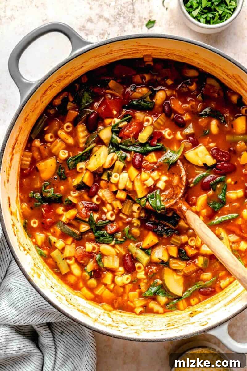 Loaded with tender veggies, beans, and pasta in a flavorful, tomato-y broth, minestrone soup is the perfect vegetarian main. Overhead view of minestrone soup simmering in a large pot, with all ingredients combined.