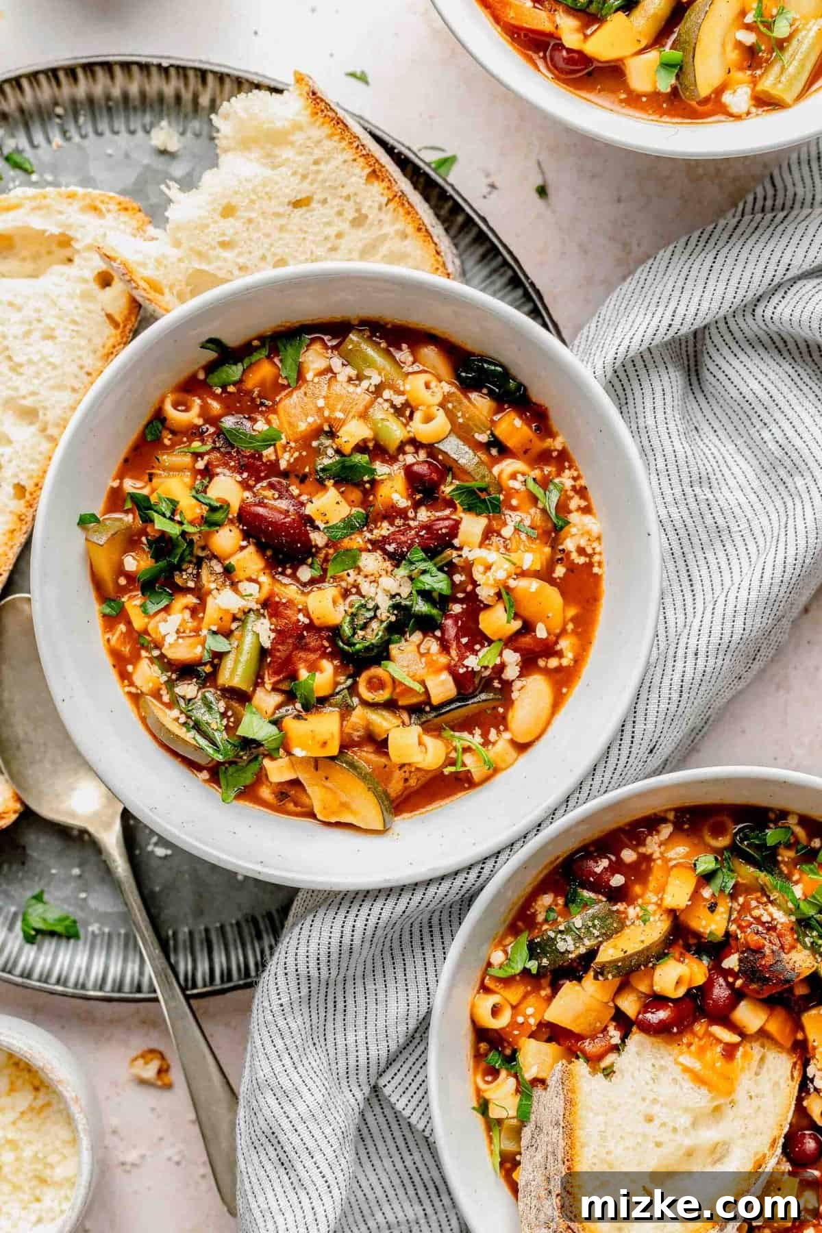 Loaded with tender veggies, beans, and pasta in a flavorful, tomato-y broth, minestrone soup is the perfect vegetarian main. Overhead shot of a single bowl of minestrone soup with a slice of crusty bread on the side.