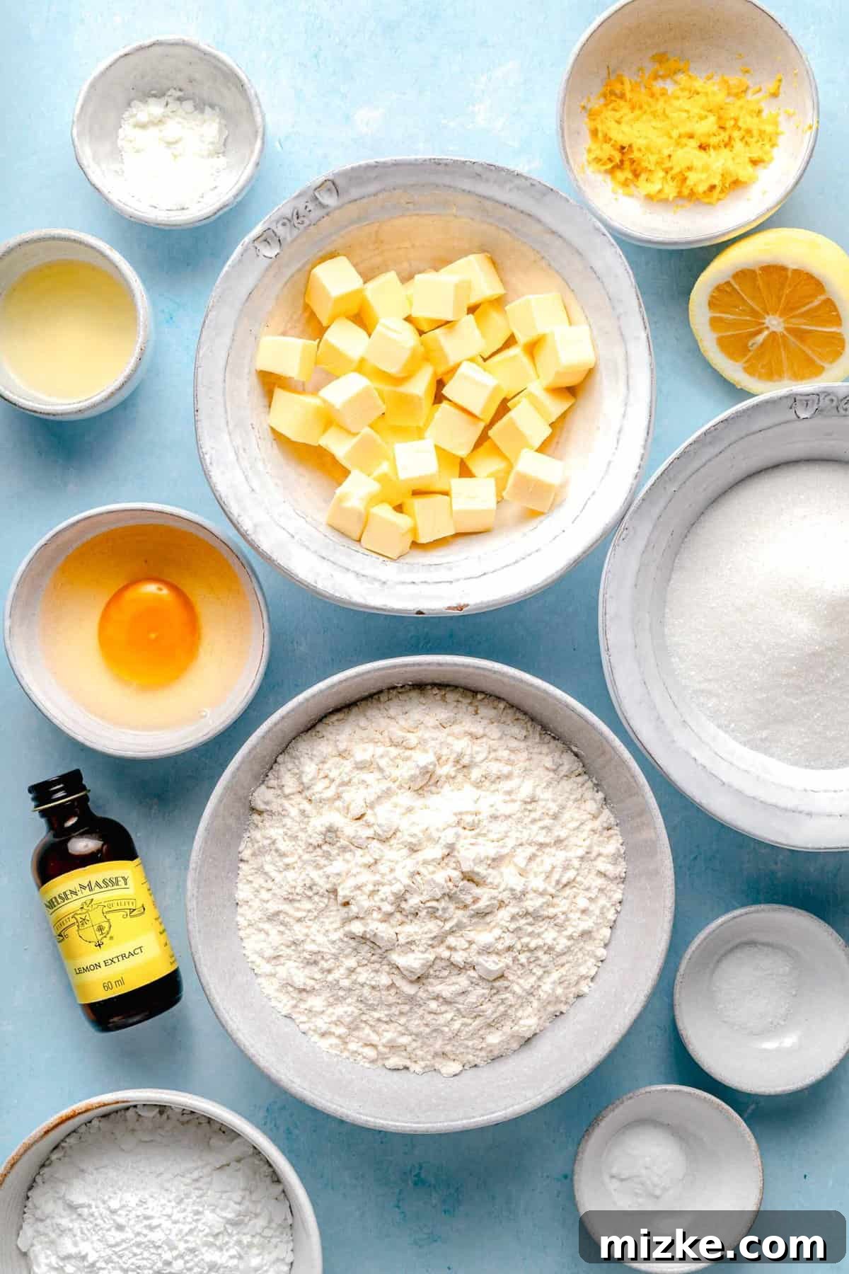 Gather your fresh ingredients to create these wonderfully soft and chewy lemon cookies. A vibrant flat lay of all the fresh and dry ingredients required to bake delicious lemon cookies, including lemons, flour, butter, sugar, and eggs, arranged neatly on a light surface.