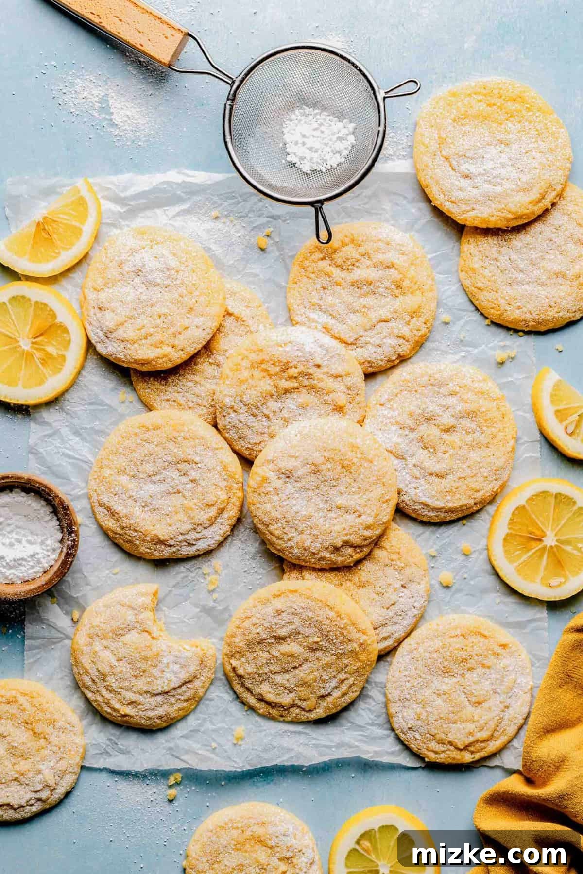 Dusting freshly baked lemon cookies with powdered sugar for a delightful finish. A close-up shot of baked lemon cookies on parchment paper, in the process of being dusted with a fine, even layer of powdered sugar from a mesh strainer held above.