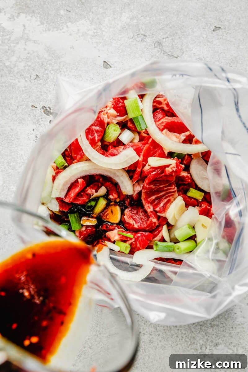Thinly sliced beef, garlic, onions, and scallions are marinated in a flavorful sauce and fried to perfection in this Korean beef bulgogi. Pouring the bulgogi marinade into a resealable bag containing thinly sliced ribeye, onions, and green onions.