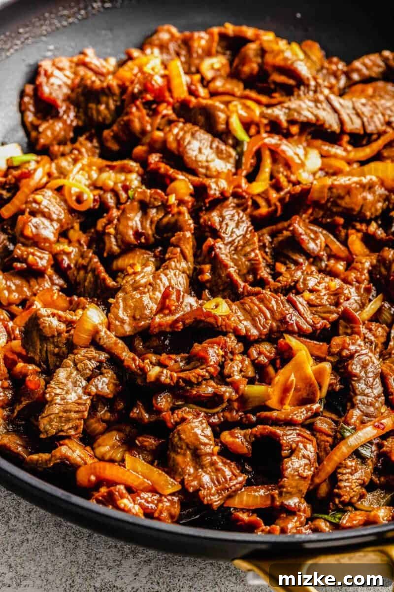 Thinly sliced beef, garlic, onions, and scallions are marinated in a flavorful sauce and fried to perfection in this Korean beef bulgogi. Cooked Korean beef bulgogi in a frying pan, ready to be served.