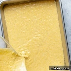 Pouring cornbread batter into a baking pan.