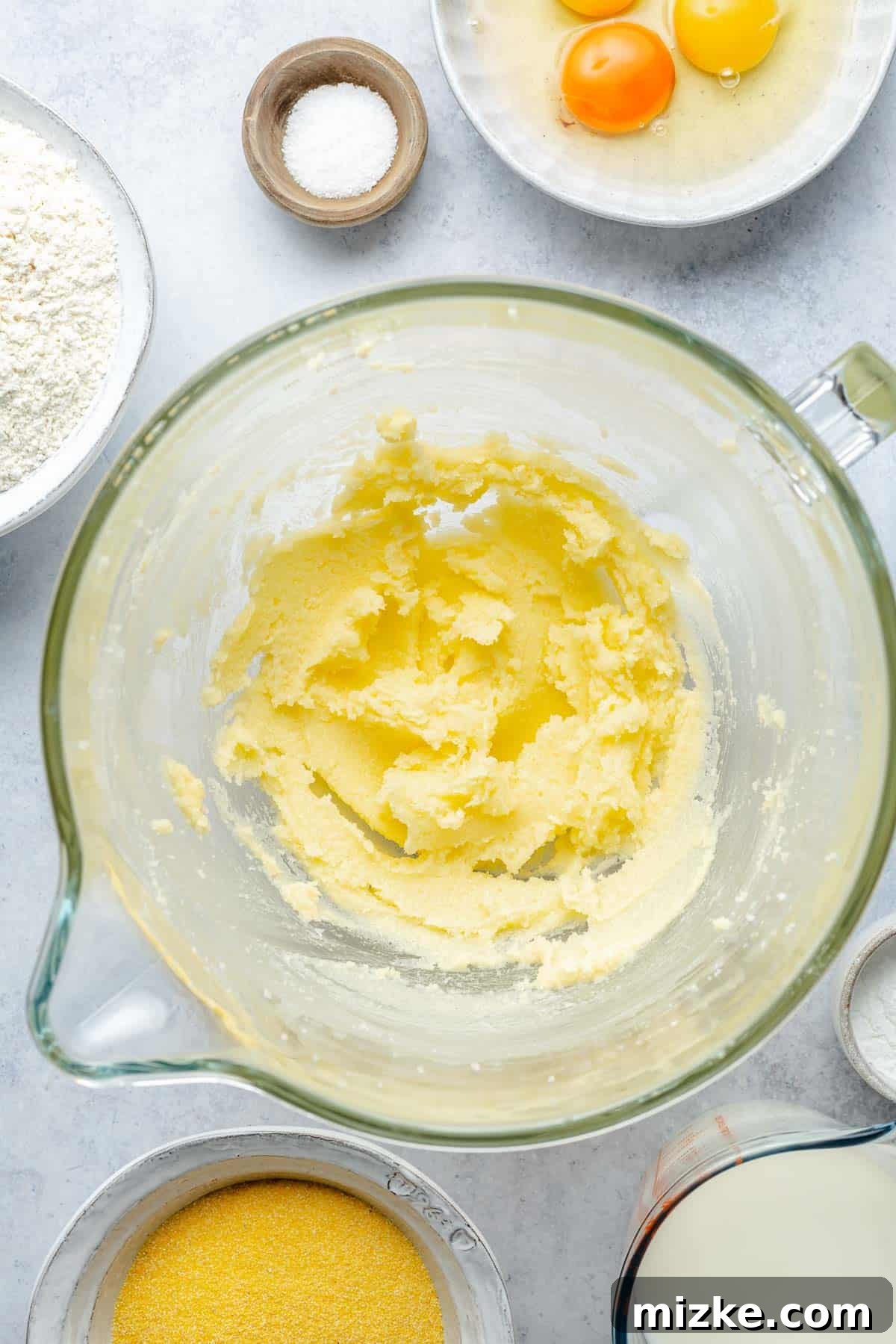 Close-up shot of butter and sugar being creamed together in a mixing bowl for cornbread batter, showing a light and fluffy texture.