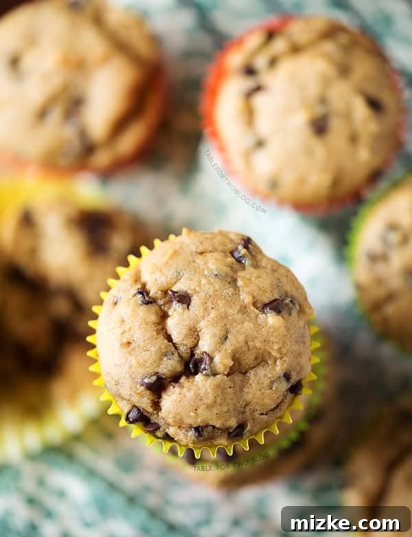 Homemade Muffins: Banana, Peanut Butter, Chocolate Chip A basket of freshly baked Banana Peanut Butter Chocolate Chip Muffins on a rustic wooden table, with whole bananas in the background. A cozy and inviting scene.