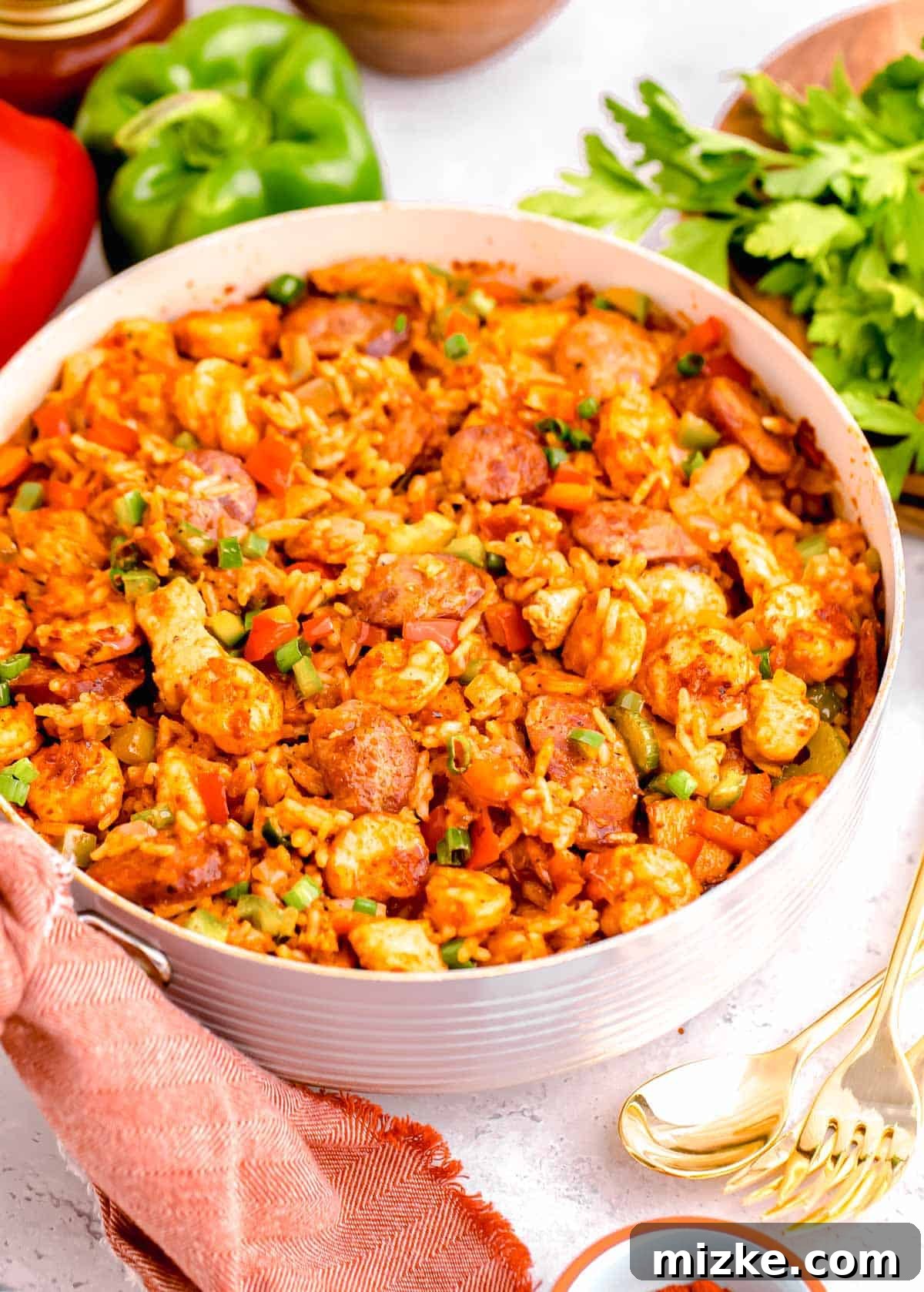 Hearty Chicken and Sausage Jambalaya 10 a large skillet of chicken and sausage jambalaya next to fresh ingredients and metal utensils