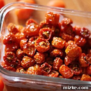 Close-up of freshly halved cherry tomatoes arranged on a parchment-lined baking sheet, seasoned and ready to be oven-dried.