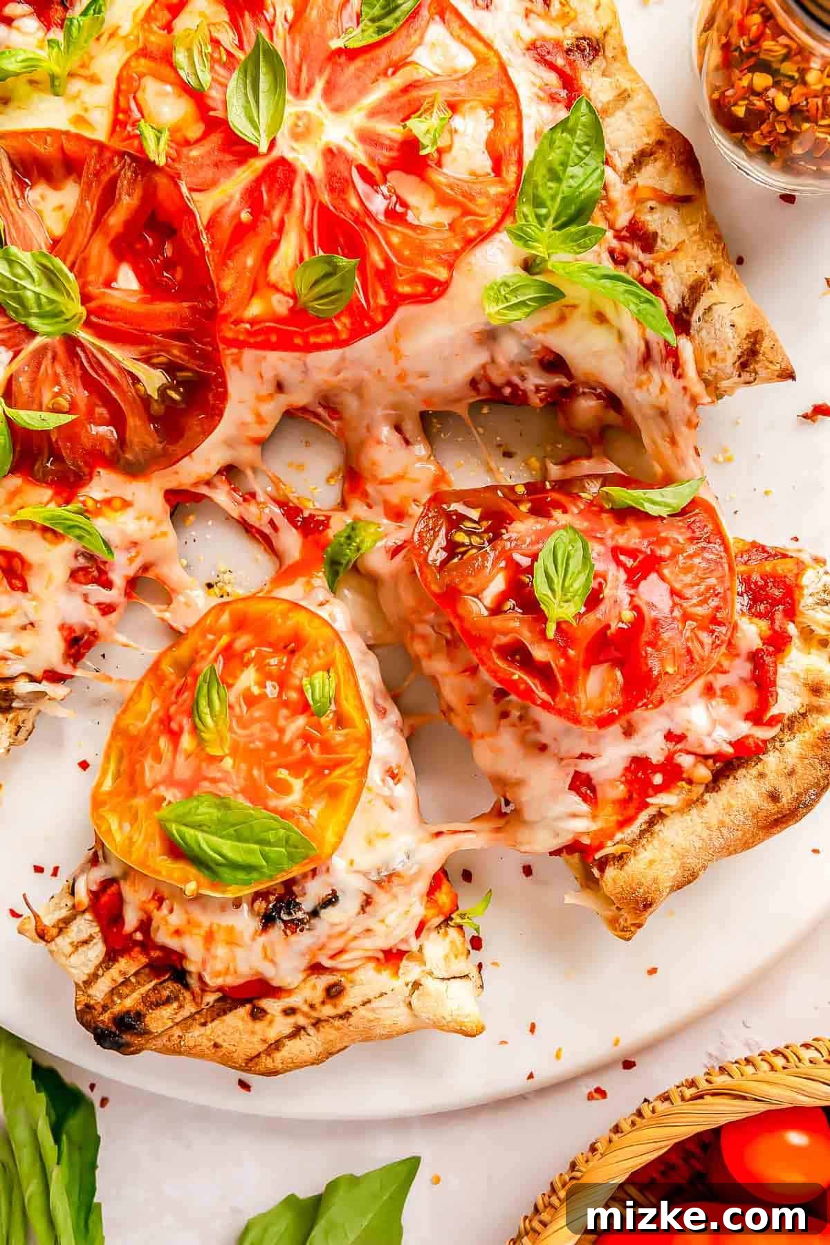 Flame-Kissed Caprese Pizza 3 Close-up of sliced wedges of grilled caprese pizza, showing the melted cheese and vibrant tomatoes