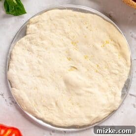 pizza dough formed into a circle on a metal pizza pan