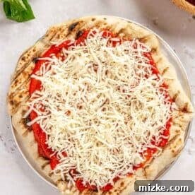shredded mozzarella cheese sprinkled on top of pizza sauce and dough