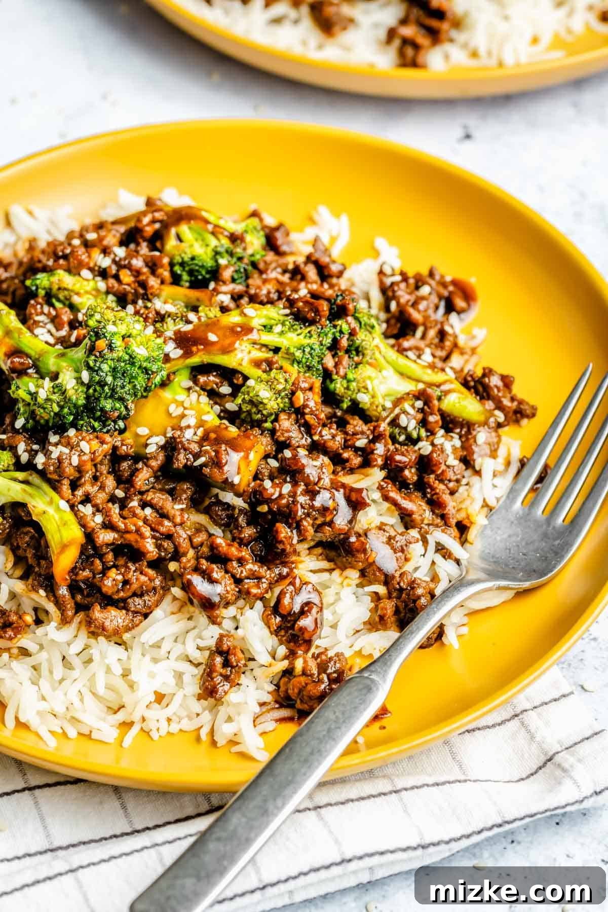 Savory Beef and Broccoli Skillet 5 A simple yet satisfying plate of ground beef and broccoli stir fry, elegantly served with jasmine rice, featuring a metal fork ready for a delicious bite.
