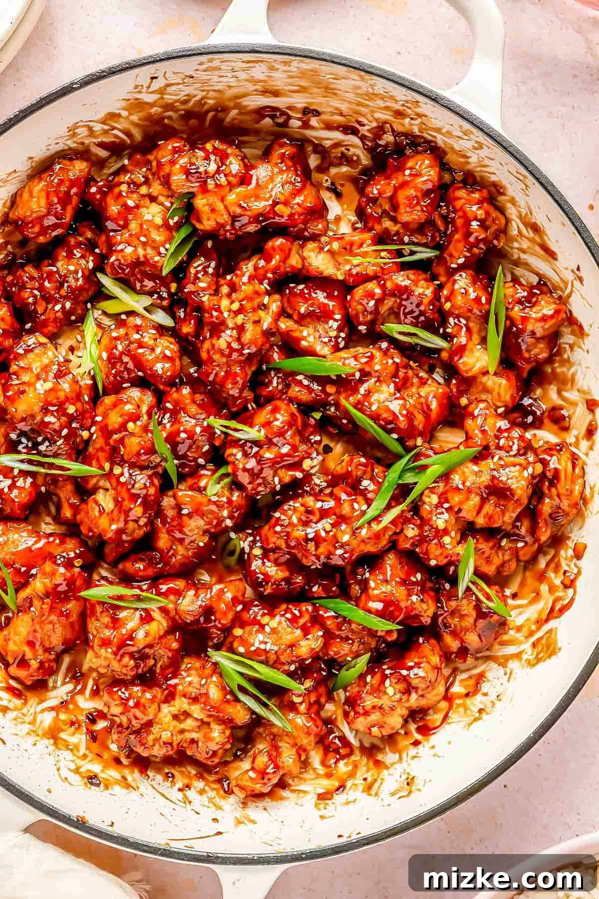 Zesty Crispy General Tsos 2 general tso's chicken in a cast iron skillet topped with white sesame seeds and fresh scallions