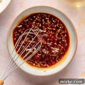 a metal whisk whisking ingredients for general tso's sauce in a bowl