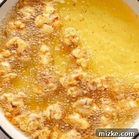 frying battered chicken in a large pot of oil