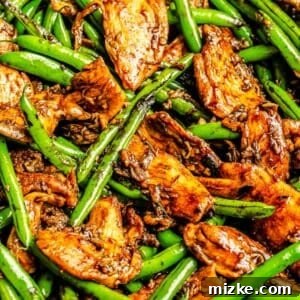 Stir fry sauce coats green beans and thinly sliced chicken in the wok, ready to be served.