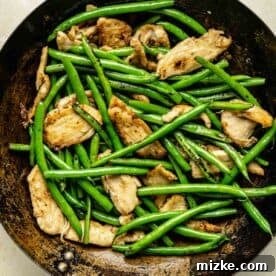 Cooked green beans and chicken mixed together in a wok.