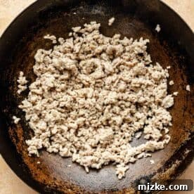 ground chicken in a wok broken into smaller pieces and cooked