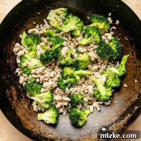 ground chicken and broccoli added to a wok