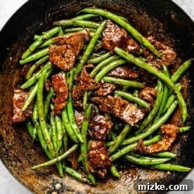 Sizzling Beef and Green Bean Stir-Fry 11 Green beans and flank steak generously coated in the rich, thickened soy sauce mixture in a wok.