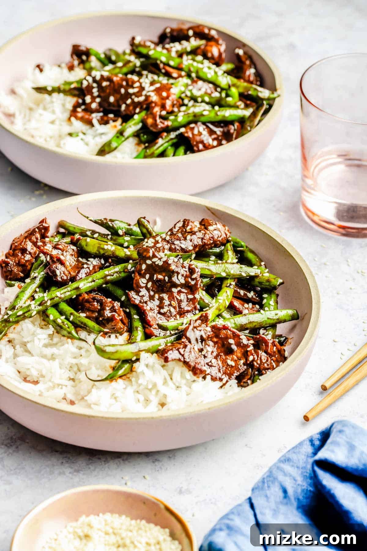 Sizzling Beef and Green Bean Stir-Fry 4 Two exquisitely presented bowls of Green Bean Beef Stir Fry, generously garnished with white sesame seeds, showcasing an inviting and appetizing presentation.