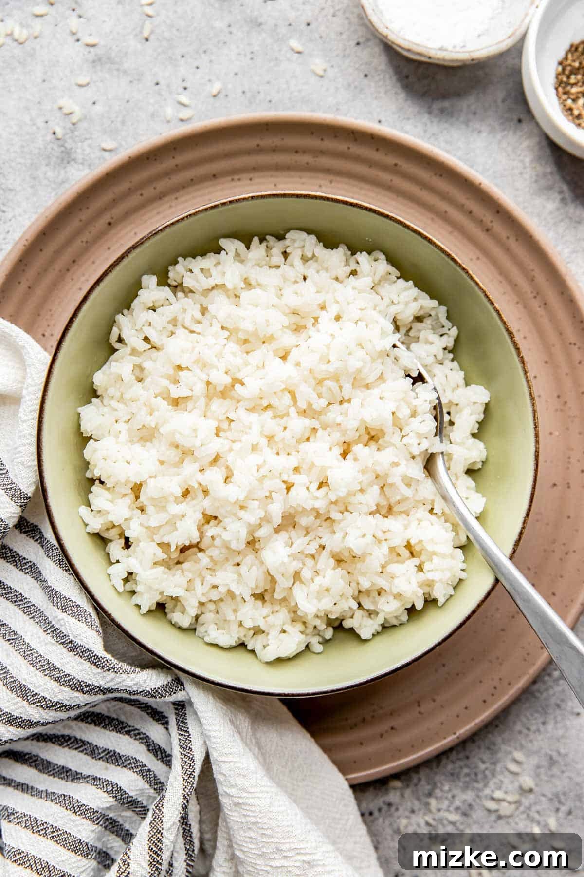 The Secret to Perfectly Fluffy White Rice 2 Cooked medium grain white rice is beautifully presented in a vibrant green bowl, resting on a brown plate, ready for serving.