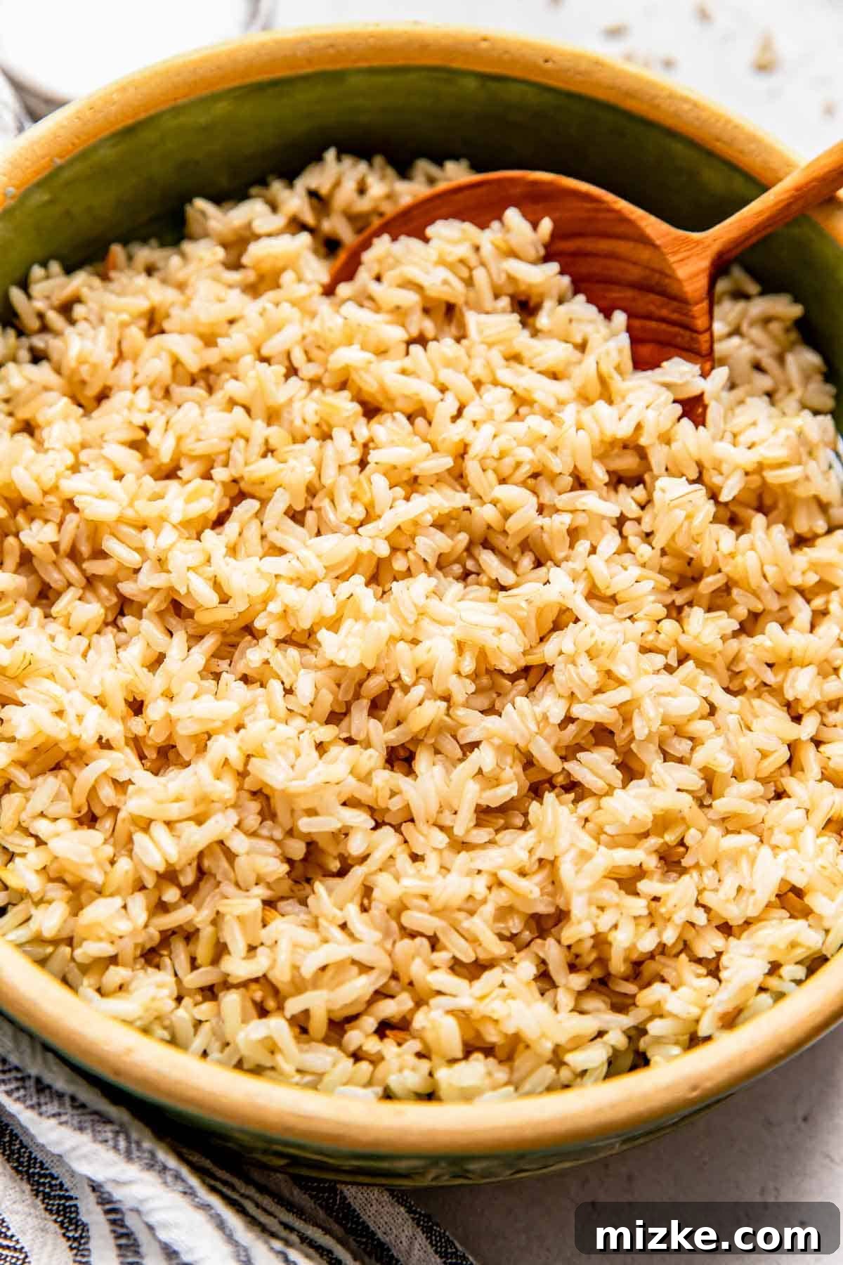 Perfect Brown Rice Every Time 6 brow rice is in a green bowl with a wooden spoon