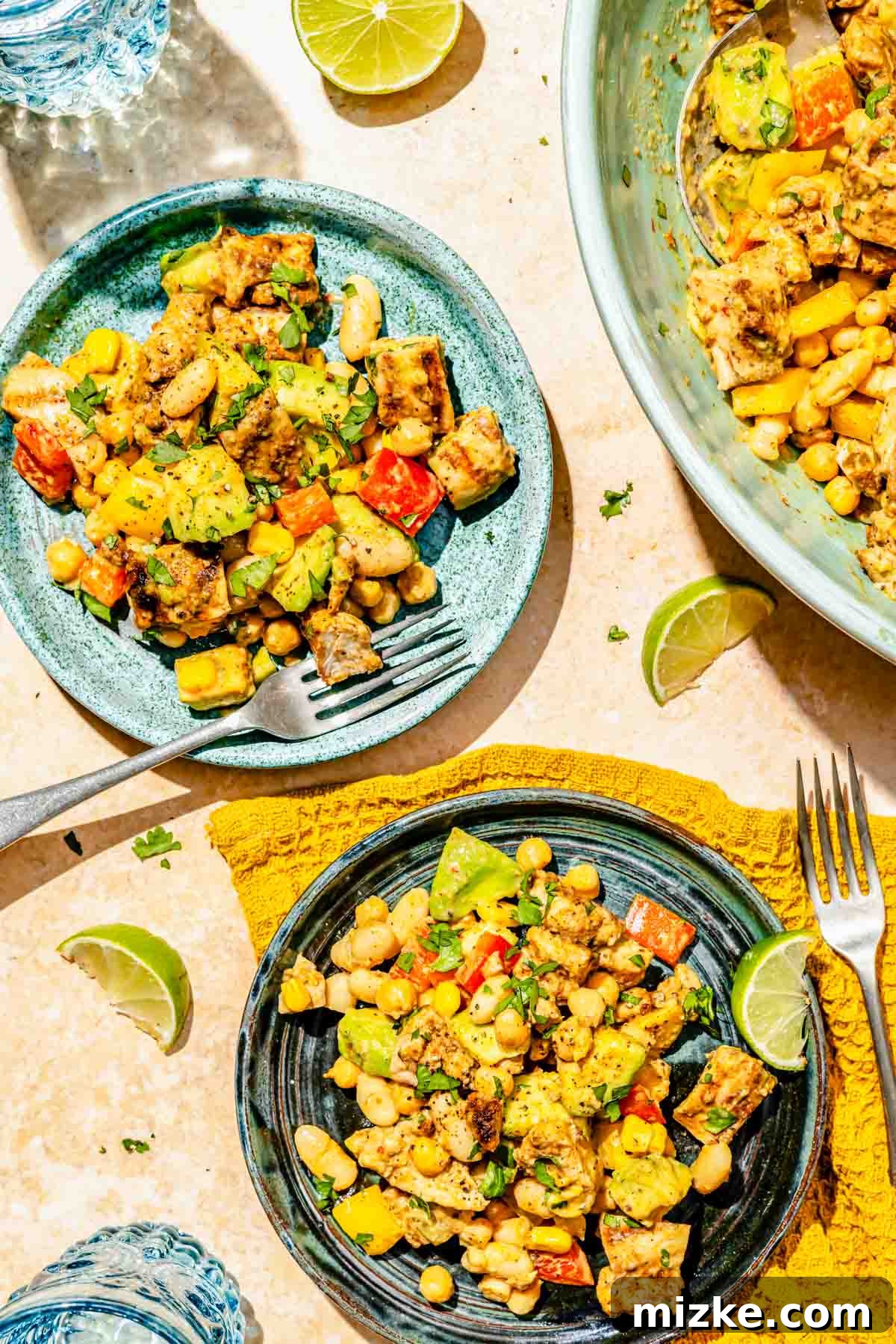 Chipotle Chicken Hearty Bean Salad 4 Individual portions of chipotle chicken dense bean salad served on several blue plates, accompanied by metal forks and a yellow linen towel, demonstrating its readiness as a complete and healthy meal.