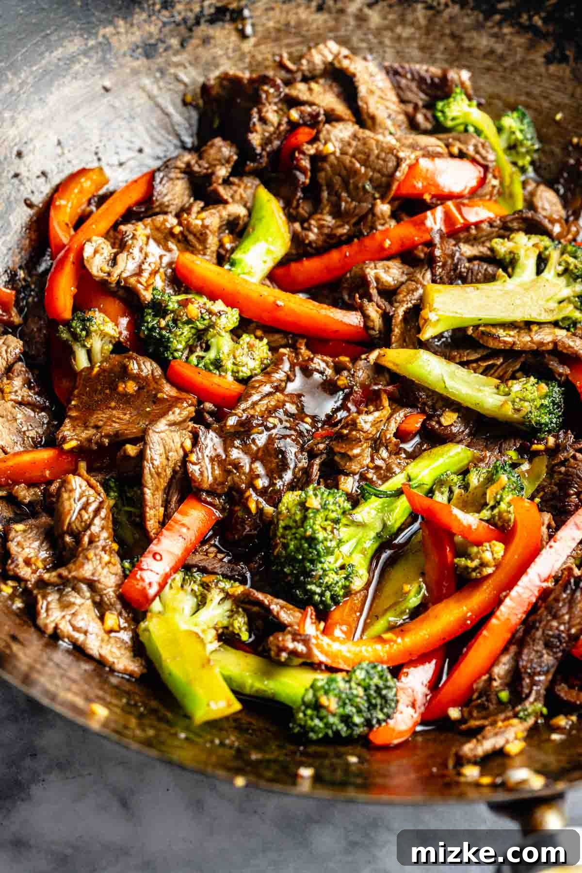 Quick-Slice Steak Stir-Fry 2 Stir-fried beef with broccoli and red bell peppers in a wok, coated in a glossy sauce.