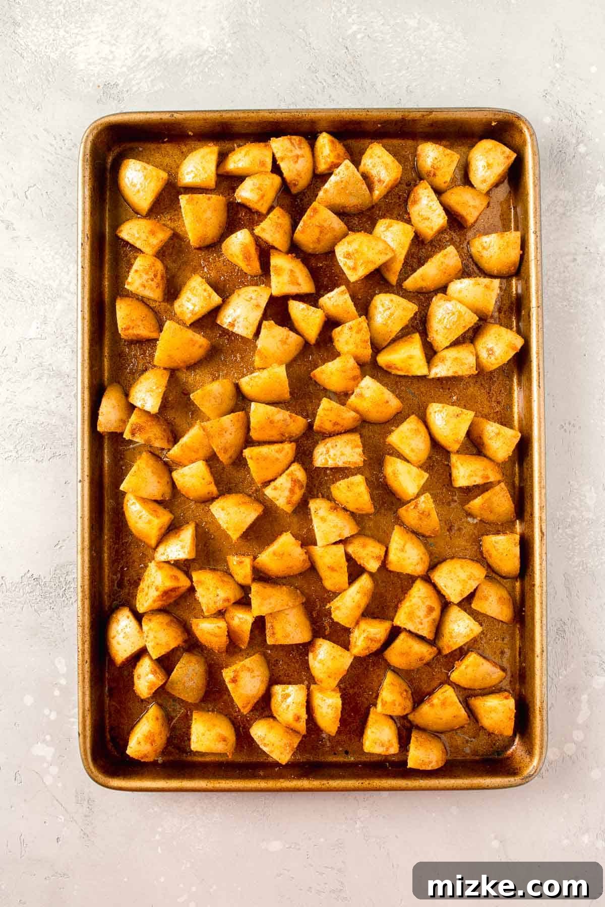 Crispy Garlic Parmesan Potatoes 6 seasoned parmesan potatoes on a rimmed metal baking sheet