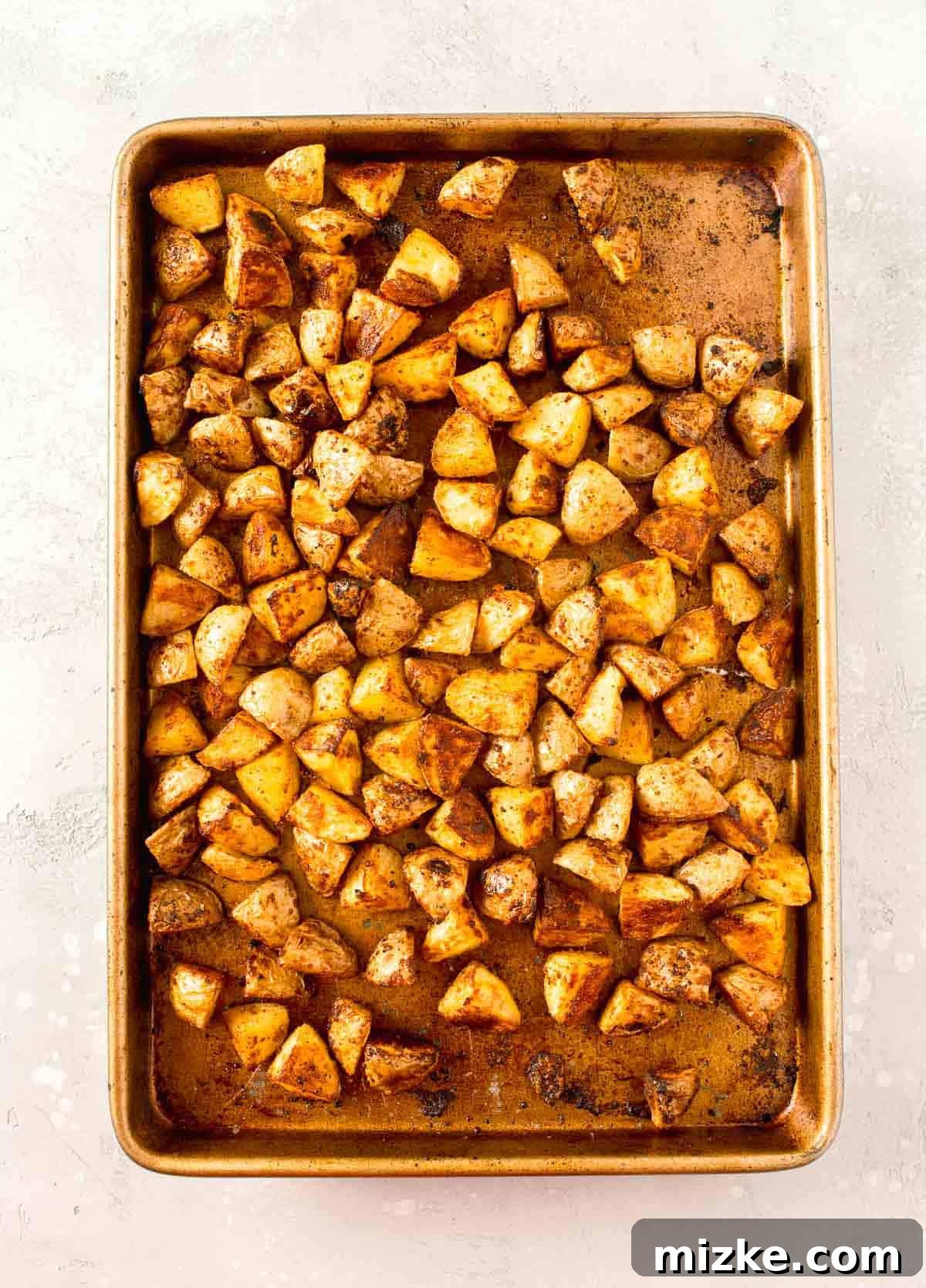 Crispy Garlic Parmesan Potatoes 7 roasted parmesan potatoes on a rimmed metal baking sheet