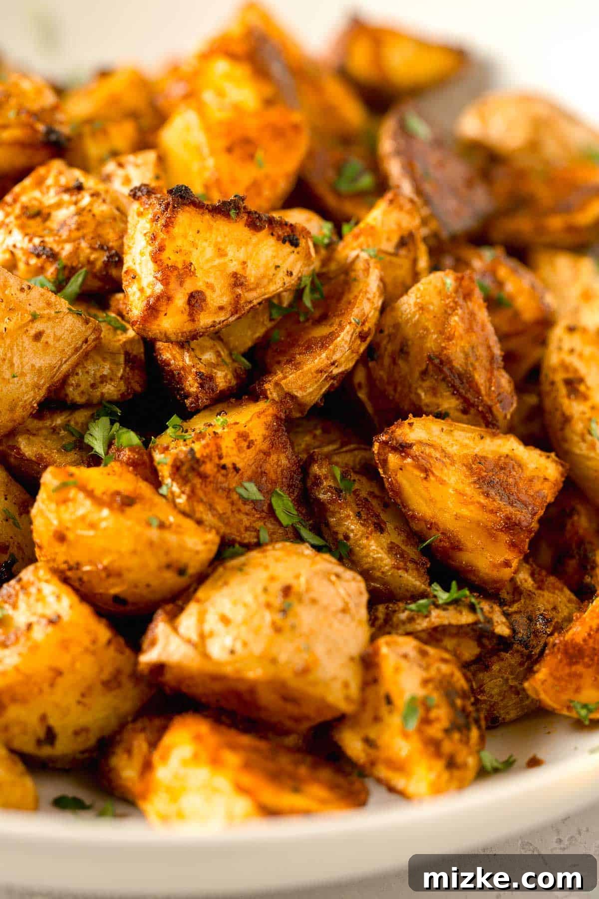 Crispy Garlic Parmesan Potatoes 9 large amount of roasted parmesan potatoes in a large white bowl with fresh parsley sprinkled on top