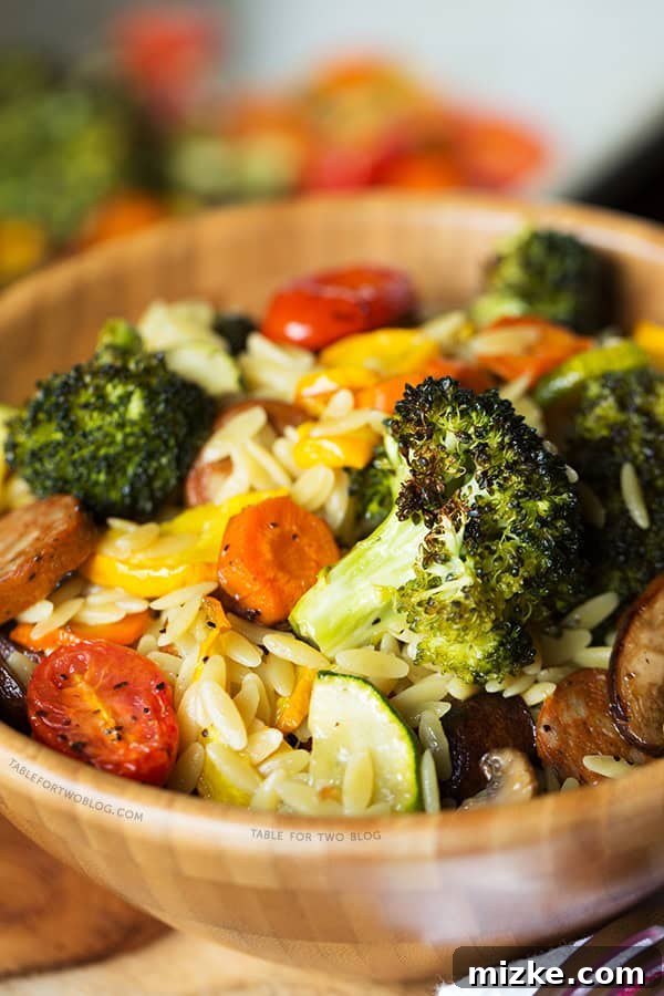 Delicious Roasted Vegetables and Andouille Orzo A vibrant bowl of Roasted Vegetables and Andouille Orzo, garnished with fresh herbs, ready to be enjoyed as a comforting and flavorful meal. | tablefortwoblog.com