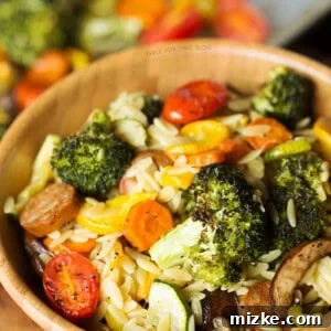 A warm, inviting bowl of Roasted Vegetables and Andouille Orzo, garnished with fresh herbs.