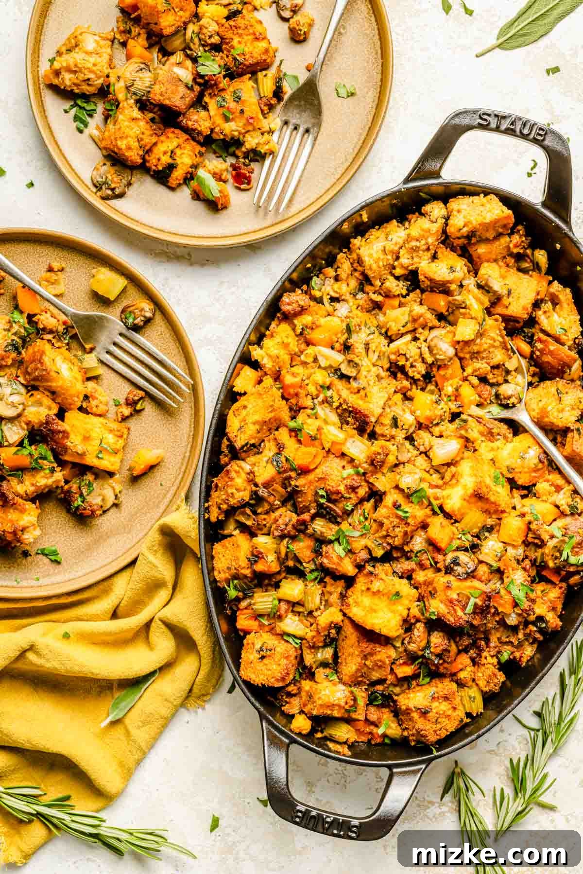 Fiery Chorizo Cornbread Bake 3 several scoops of chorizo cornbread stuffing has been dished out from an oval cast iron baking dish onto brown plates