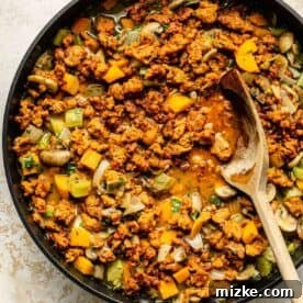 Fiery Chorizo Cornbread Bake 7 chorizo and vegetables simmering in a nonstick skillet with a wooden spoon