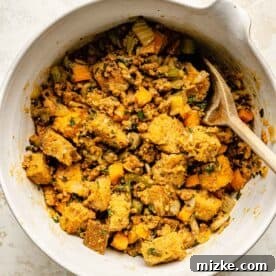 Fiery Chorizo Cornbread Bake 8 cornbread, sourdough, chorizo, and vegetable mixture in a ceramic bowl with a wooden spoon