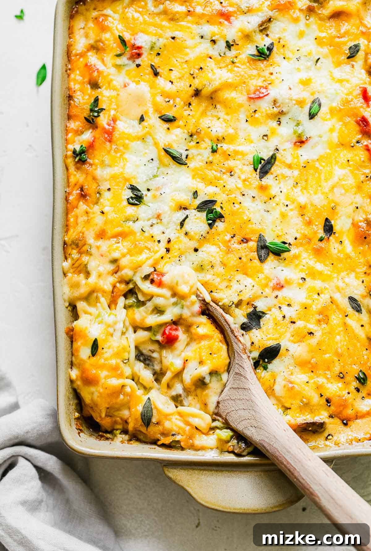 Cheesy Spaghetti Bake 2 A wooden spoon scooping into the creamy baked spaghetti casserole, showcasing its rich texture and ingredients.